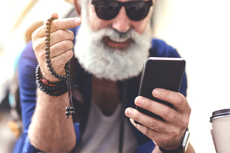 Happy senior male traveler with rosary and phone