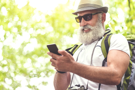 Happy old man using smartphone in nature