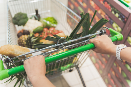 Female arms holding supermarket trolleyの写真素材