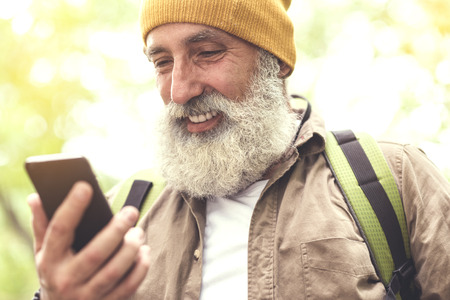 Happy senior tourist using phone for finding locationの写真素材