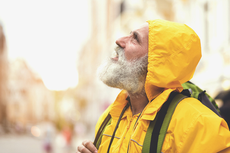 Pensive senior man walking in city while rainingの写真素材