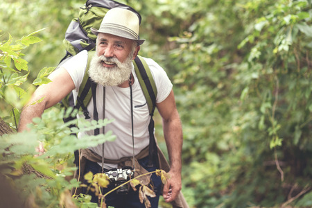 Cheerful old man enjoying walk near treesの写真素材