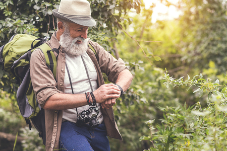 Cheerful senior male hiker using his wristwatchの写真素材