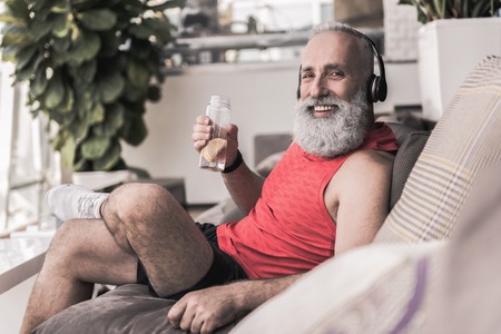 Cheerful old male is sitting on couch in sport centerの写真素材