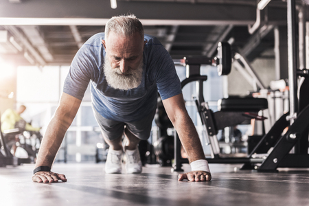 Bearded mature pensioner male is having workout in athletic clubの写真素材