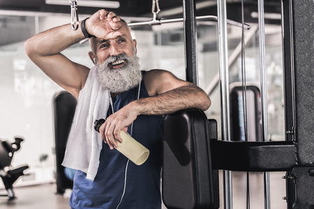 Joyful mature male having rest after workout in sport center