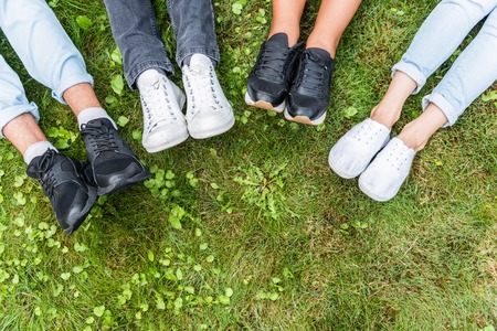 Close up top view of feet with sneakers of young men and women lying on grass. Copy spaceの写真素材
