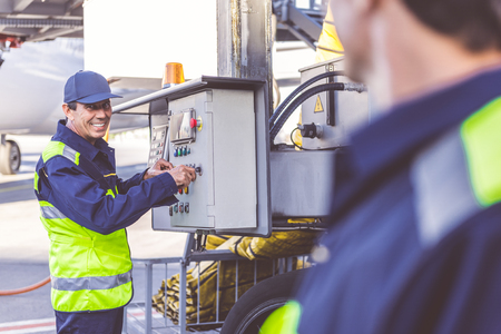 Cheerful worker controlling tool at airdrome