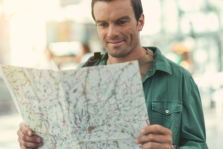 Cheerful adult guy is considering his travel itinerary
