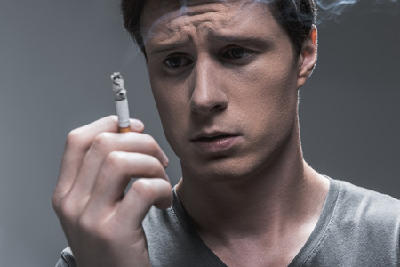 Young man expressing hesitation about smokingの写真素材