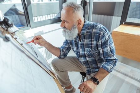 Skillful old architect is laboring in officeの写真素材