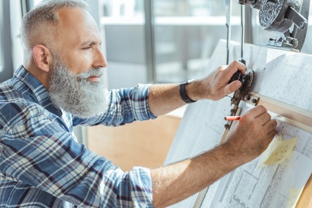Pleasant serious old man is working on professional board
