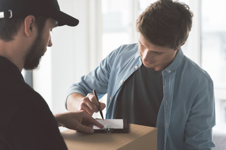 Serene courier giving package to happy customerの写真素材