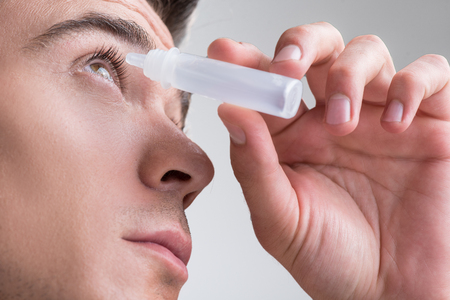Attractive guy is using medical product for eyeballの写真素材