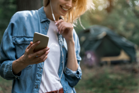 Happy young woman listening to music in forestの写真素材