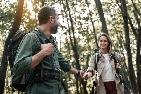 Happy man leading hand of woman in forestの写真素材