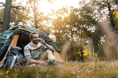 Cheerful male tourist speaking by cellphone in the natureの写真素材