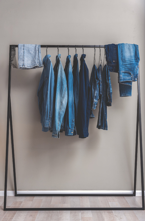 Various blue jean shirts and trousers are at hangers in wardrobe. Copy space. Nobodyの写真素材
