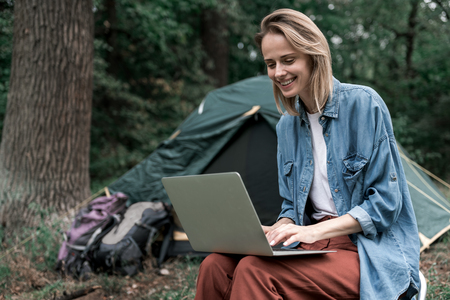 Positive girl typing on laptop in the natureの写真素材