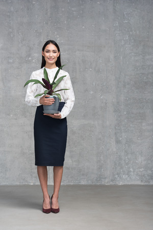 Outgoing girl keeping big green plantの写真素材