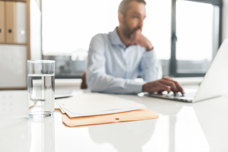 Thoughtful businessman typing on deviceの写真素材
