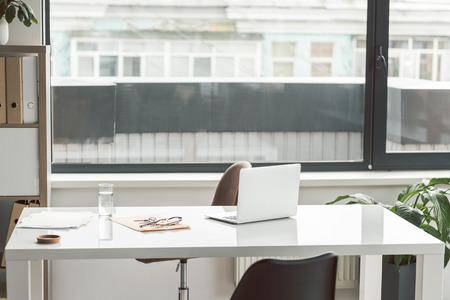 Modern open laptop is near papers on desk. Workspace in office. Nobody. Copy spaceの写真素材