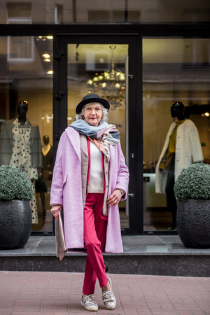 Elegant senior woman standing near boutique on streetの写真素材