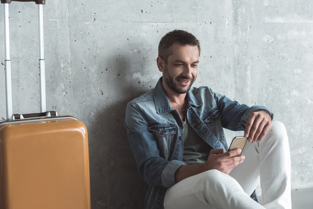 Charming elegant guy with stubble is holding mobile phoneの写真素材
