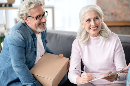 Cheerful mature husband and wife signing document of delivery serviceの写真素材