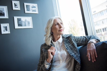 Elegant serious businesswoman is sitting on couchの写真素材