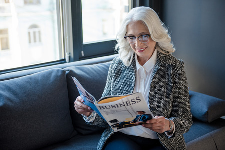 Joyful elegant woman is holding magazineの写真素材