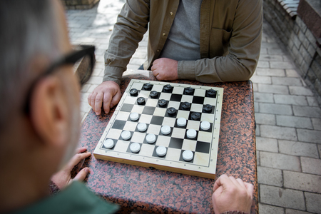 Two senior men playing checkers outdoorの写真素材