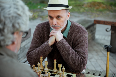 Thoughtful mature man expressing seriousness during chess gameの写真素材