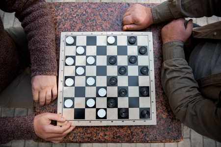 Mature male friends playing draughts outdoorの写真素材