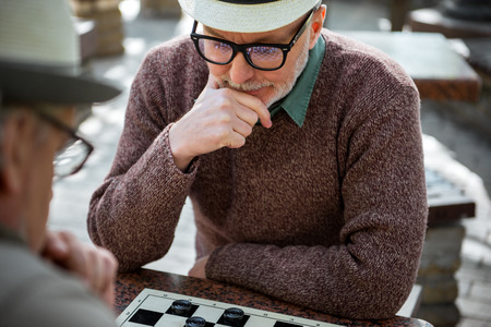 Mature male pensioner thinking about next move in checkersの写真素材