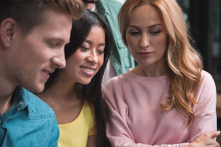 Listening carefully. Selective focus of young positive asian woman who is looking forward with members of her team. They are developing strategy of new business projectの写真素材
