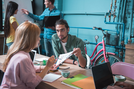 Progressive thinking. Selective focus of concentrated young guy is sitting at workplace and holding...