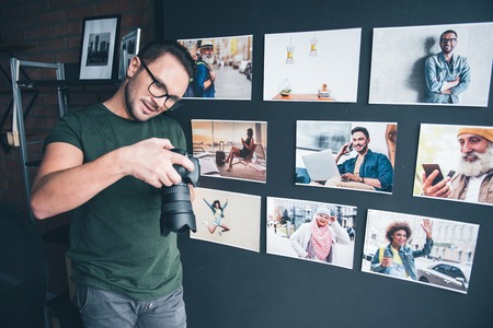 Portrait of smiling bearded man looking at camera while situating near wall. He keeping it in hand. Job and hobby conceptの写真素材