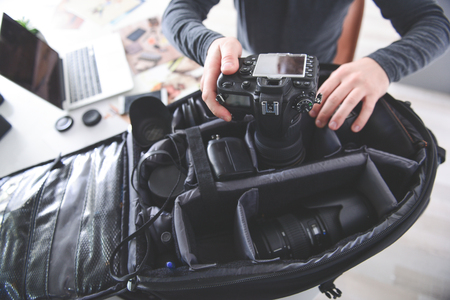 Top view close up photographer arm putting digital device for taking photos in case. He sitting at...