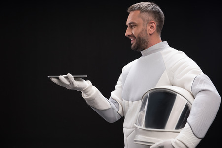 Modern technologies. Side view profile of optimistic bristled spaceman wearing protective suit is...