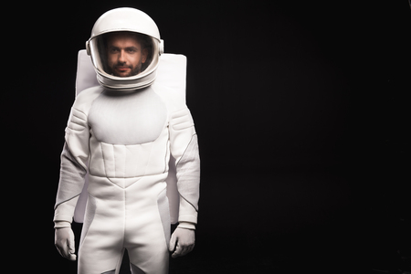 Ready for new discovery. Portrait of concentrated young cosmonaut wearing hyperbaric astronaut protective suit is standing and looking at camera confidently. Isolated background with copy spaceの写真素材