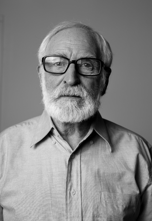 Waist up black-and-white portrait of thoughtful pensioner standing. Isolated on grey backgroundの写真素材