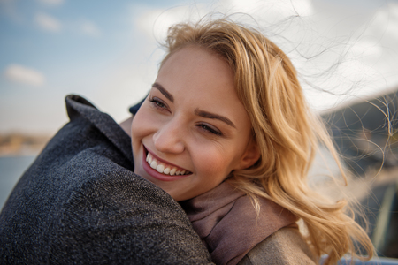 Long-awaited meeting. Close up portrait of young woman in arms of boyfriend while smiling and standingの写真素材