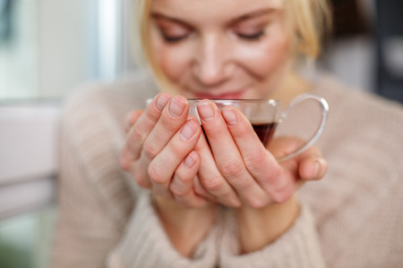 Close up of female holding mug of tasty beverage. Focus on hands with cupの写真素材