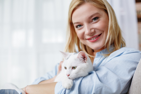 Waist up portrait of joyful girl hugging darling pet. She is looking at camera and laughing. Copy space in left sideの写真素材