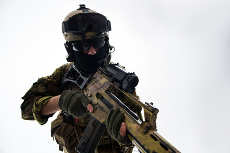 Portrait of serious defender in helmet and balaclava keeping assault rifle. War concept. Isolated