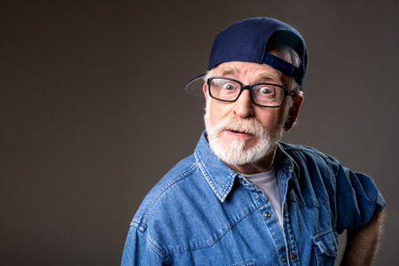 Portrait of surprised aging man standing and staring at camera with amazement. Isolated on grey backgroundの写真素材
