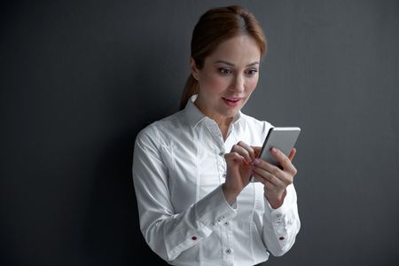 Portrait of surprised female looking at mobile while holding it in hand. Digital device and labor conceptの写真素材