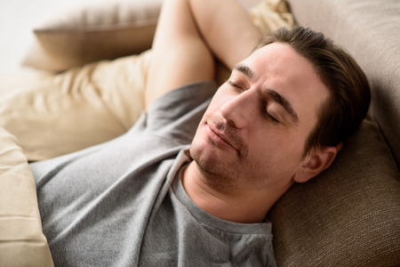 Tranquil man slumbering on bed. His eyes are closed with serenity. Relaxation concept