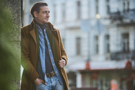 Smiling tourist leaning against wall while standing outside. Relax concept. Copy spaceの写真素材